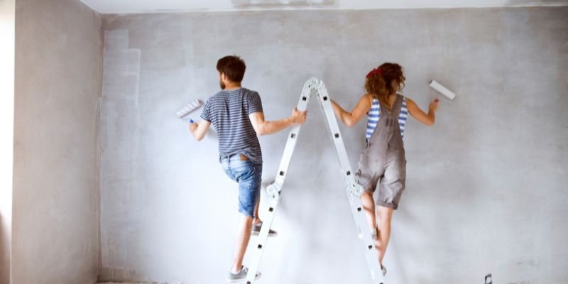 A couple painting the wall of their fix and flip investment property - ECF