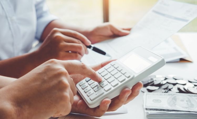 A couple working out the interest rates for their fix and flip loan with a calculator - Express Capital Financing