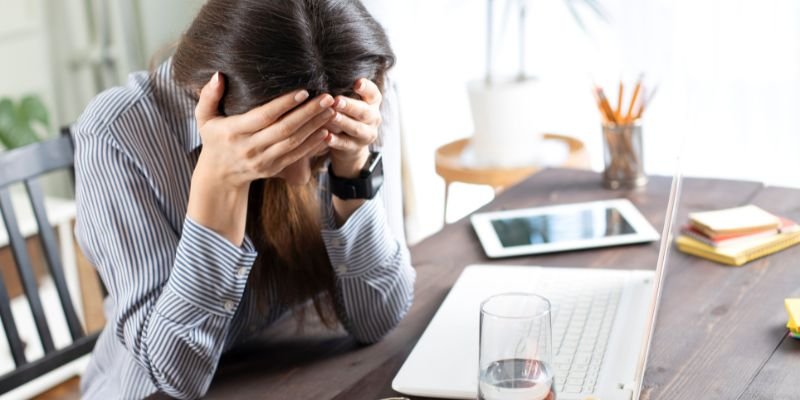 A real estate investor at her laptop with her head in her hands after making a common mistake - ECF