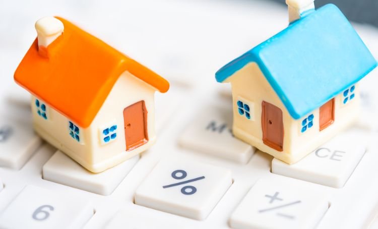 Two toy houses on a keyboard next to the % key representing the rising interest rate on fix and flip properties - Express Capital Financing