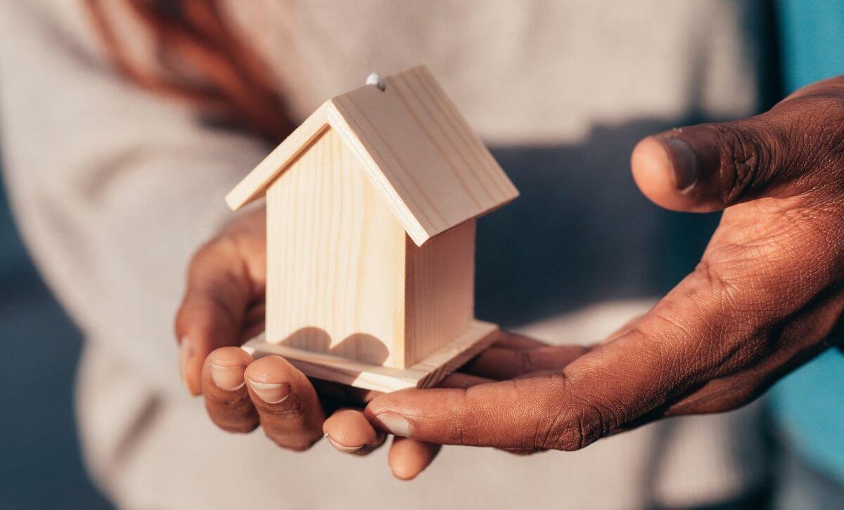 Someone holding a small wooden house  - Volatility of market rates - Express Capital Financing