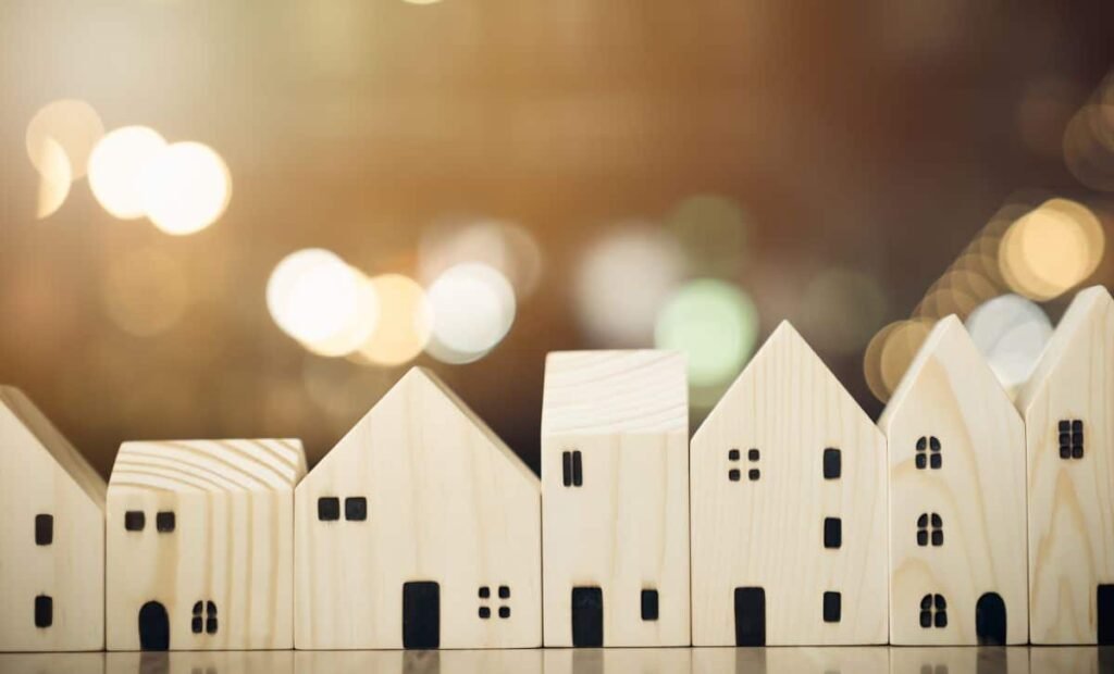 a row of small wooden models of houses in front of twinkling lights