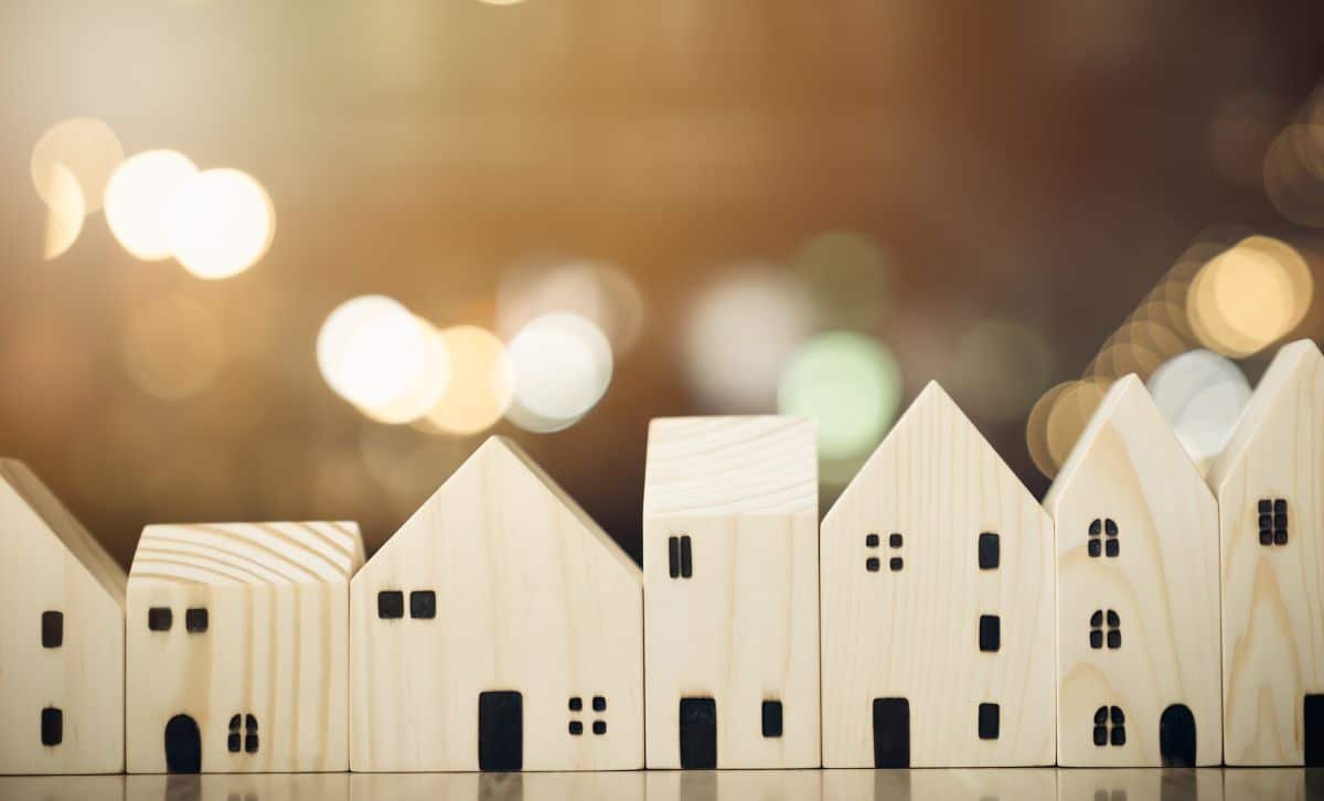 a row of small wooden models of houses in front of twinkling lights